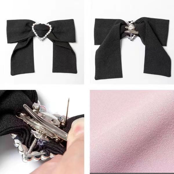 Close-up of a pink and black long sleeved blouse, showing the detachable black bow brooch with a pearl heart centre and brooch pin fastening at the back. Displayed against a white background.