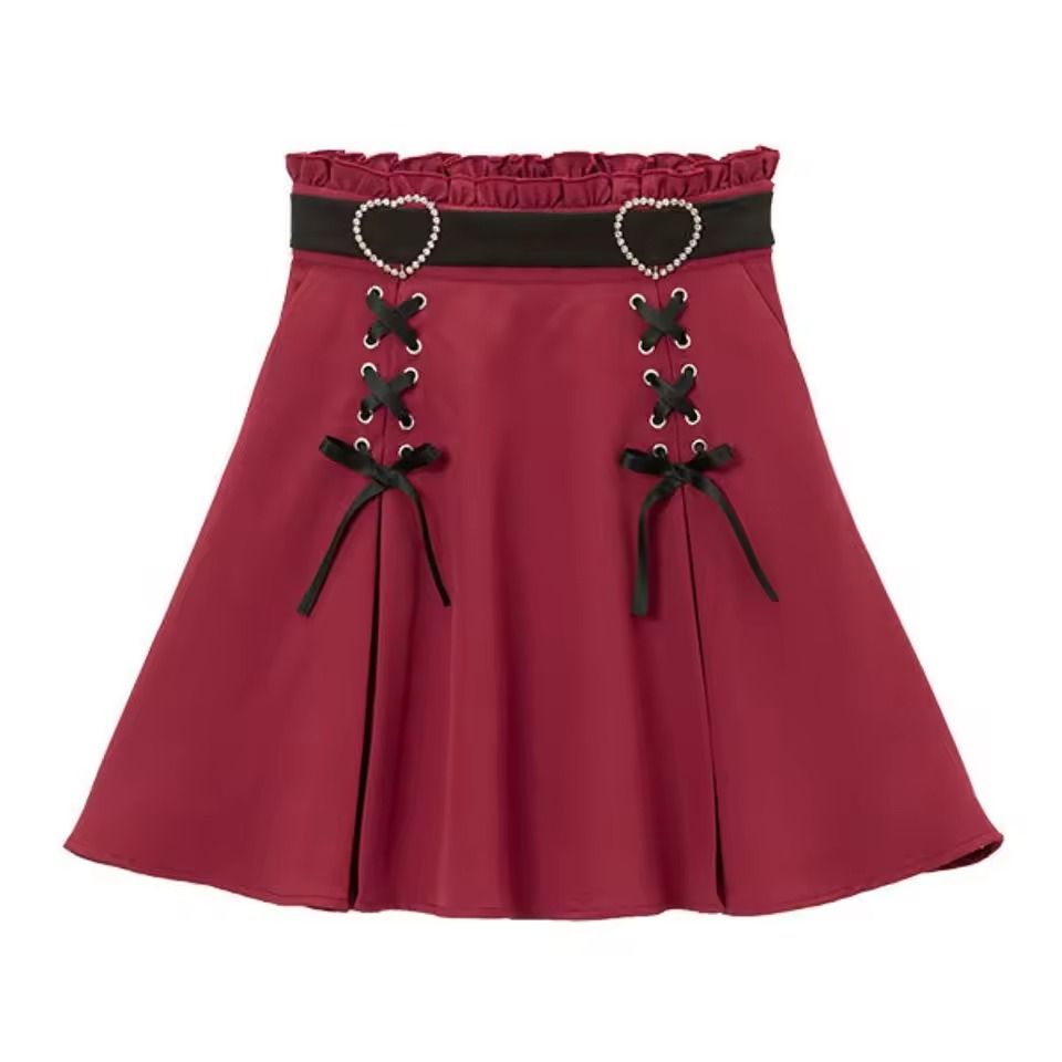 Red and black high waisted skirt featuring a ruffled waist, diamante heart shaped buckle belt, black satin ribbon corset lacing and pleated a-line design, displayed against a white background.