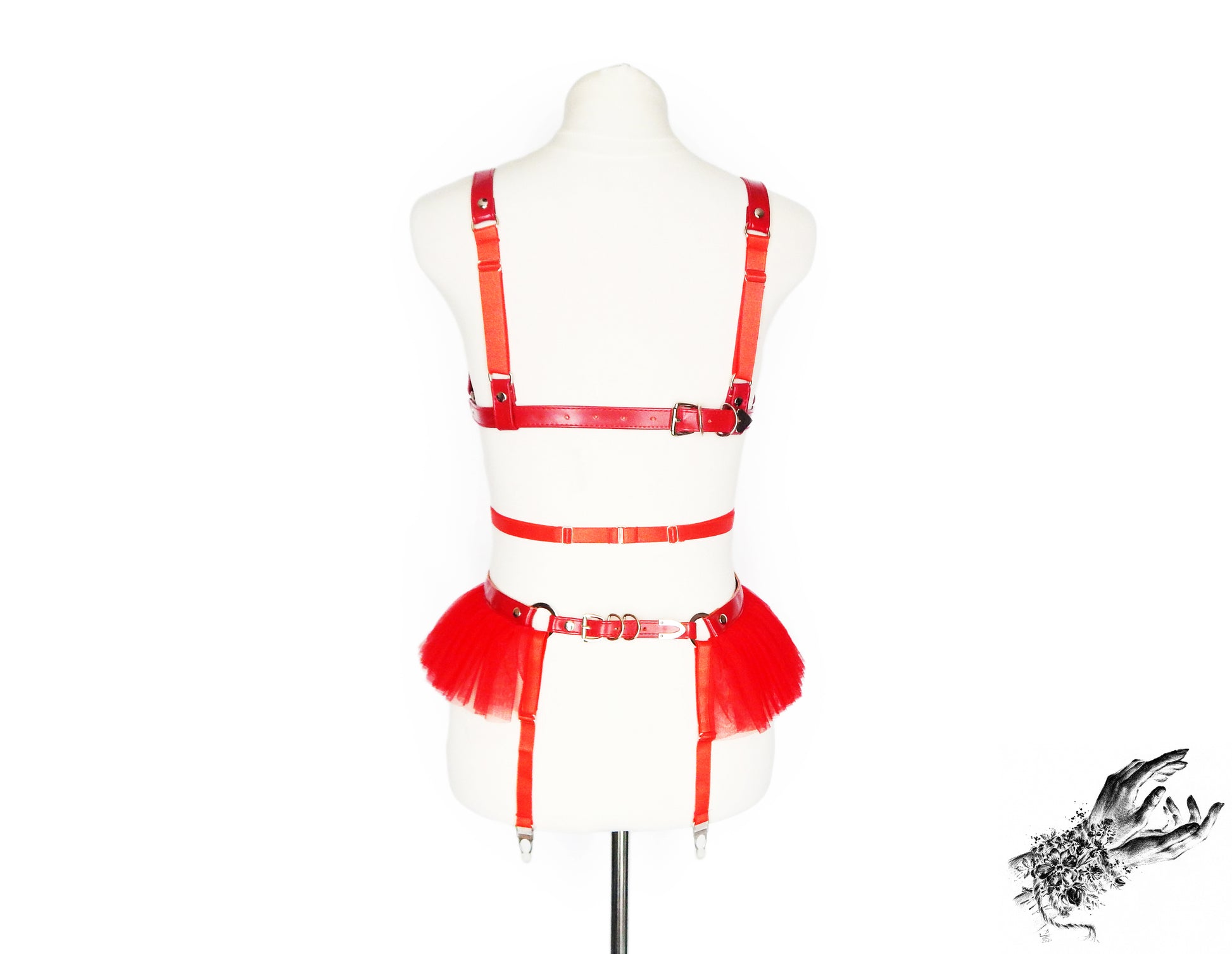 Rear view of a red vegan leather harness set featuring a separate harness bra and garter belt with adjustable elastic and buckled faux leather straps, displayed on a mannequin against a white background.