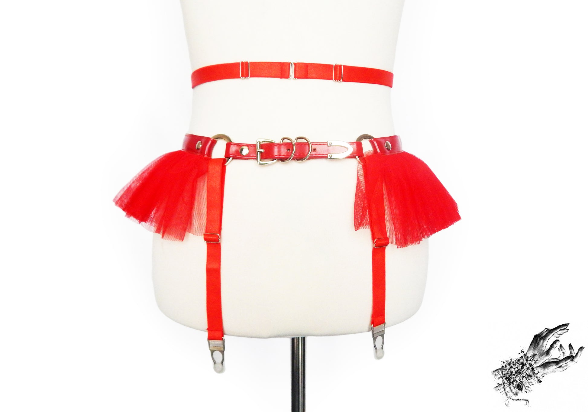 Rear view of a red faux leather garter belt showing the adjustable elastic waist and suspender straps and buckled vegan leather hip strap, displayed on a mannequin against a white background.