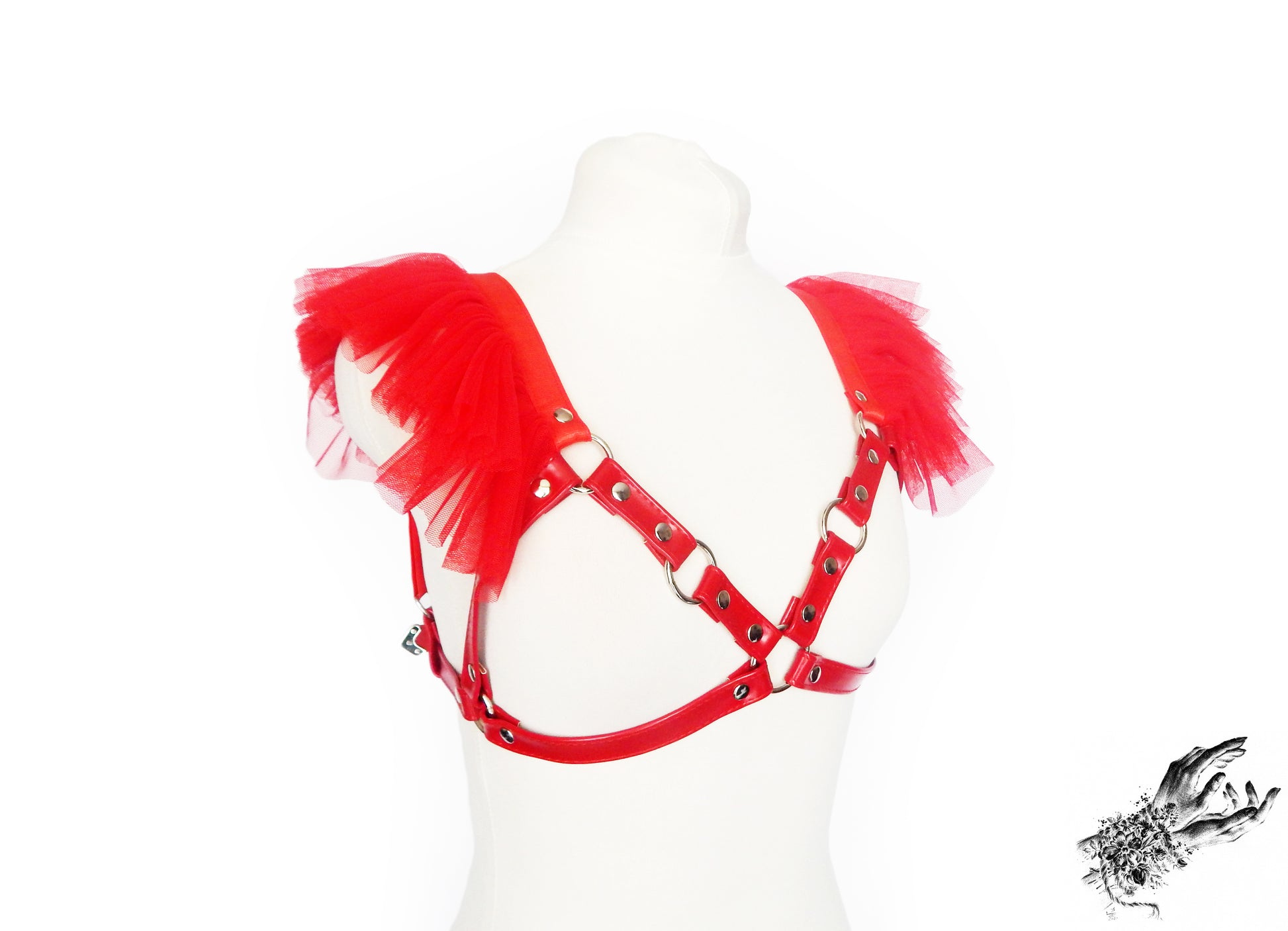 Red vegan leather harness bra featuring ruffled tulle accents at the shoulders, silver O ring hardware and adjustable shoulder and back straps, displayed on a mannequin against a white background.
