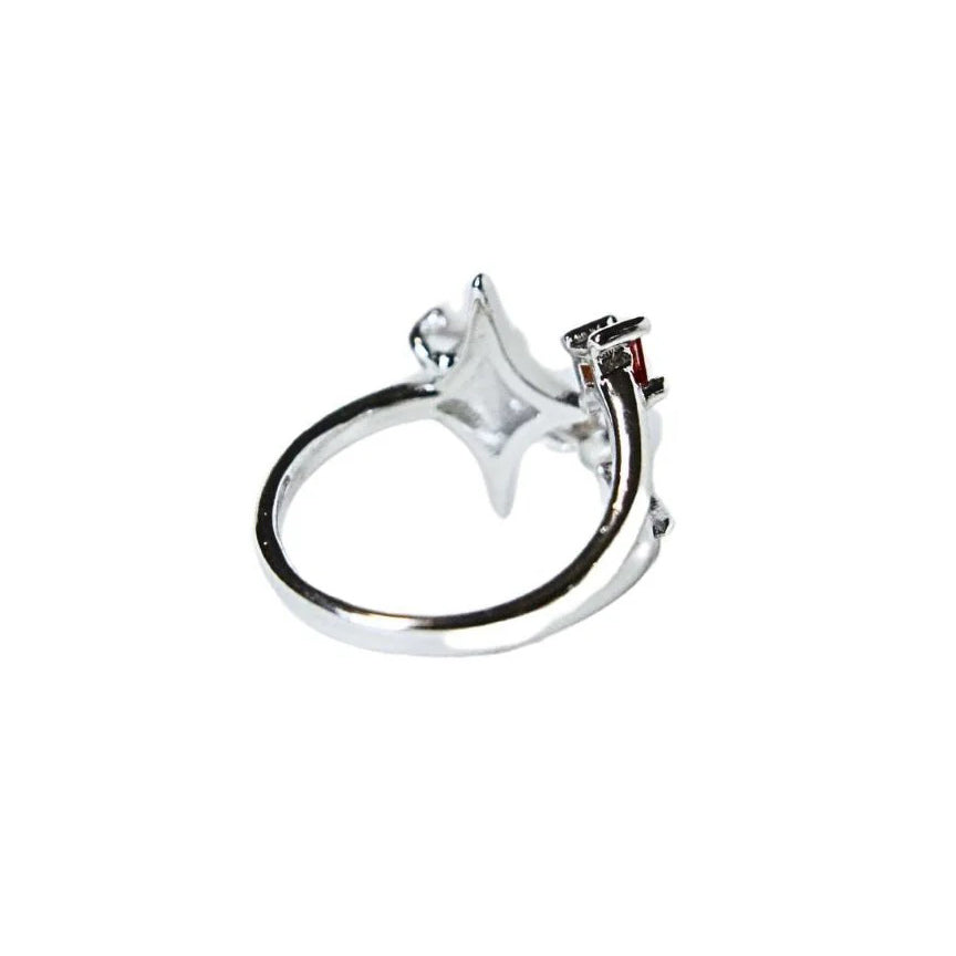 A silver ring featuring a star-shaped setting with a small red gemstone and open adjustable band, shown on a plain white background.