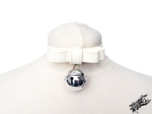 White faux leather bow choker featuring a silver bell design, displayed on a white mannequin bust