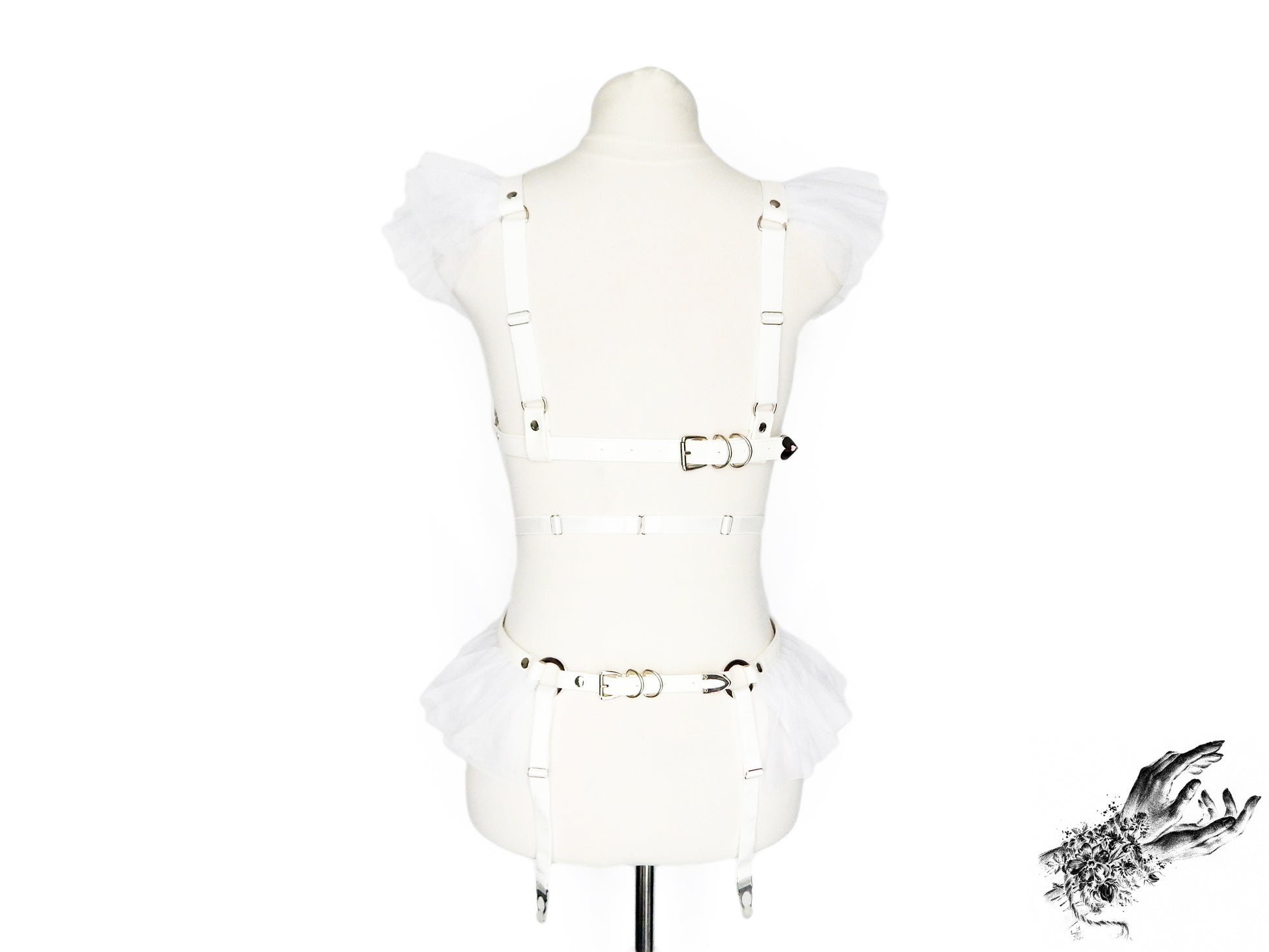 Rear view of a white vegan leather harness set featuring a separate harness bra and garter belt showing the adjustable elastic shoulder and suspender straps with buckled faux leather back straps, displayed on a mannequin against a white background.