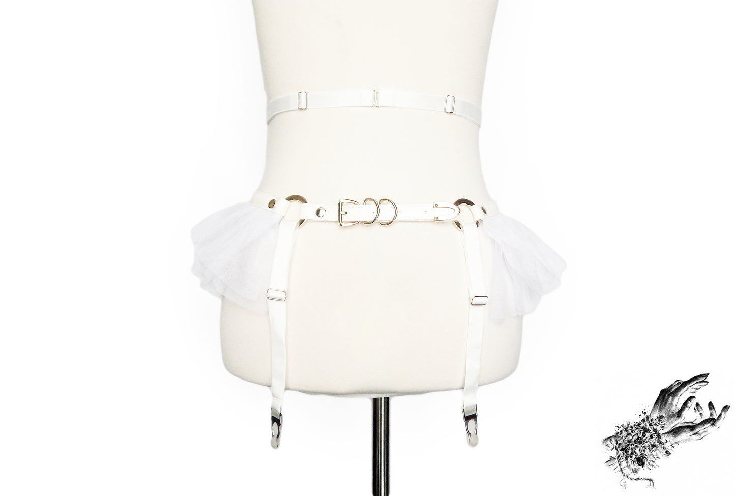 Rear view of a white faux leather garter belt featuring adjustable elastic waist and suspender straps and buckled vegan leather hip strap, displayed on a mannequin against a white background.