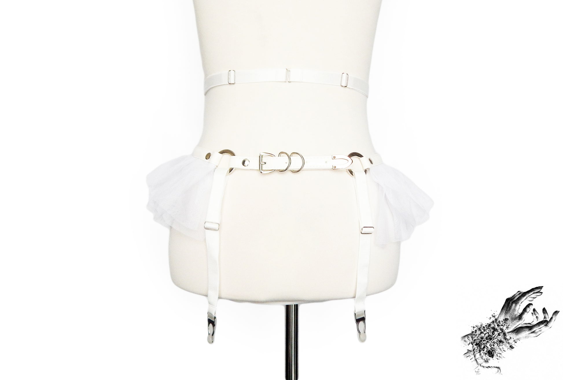 Rear view of a white faux leather garter belt featuring adjustable elastic waist and suspender straps and buckled vegan leather hip strap, displayed on a mannequin against a white background.