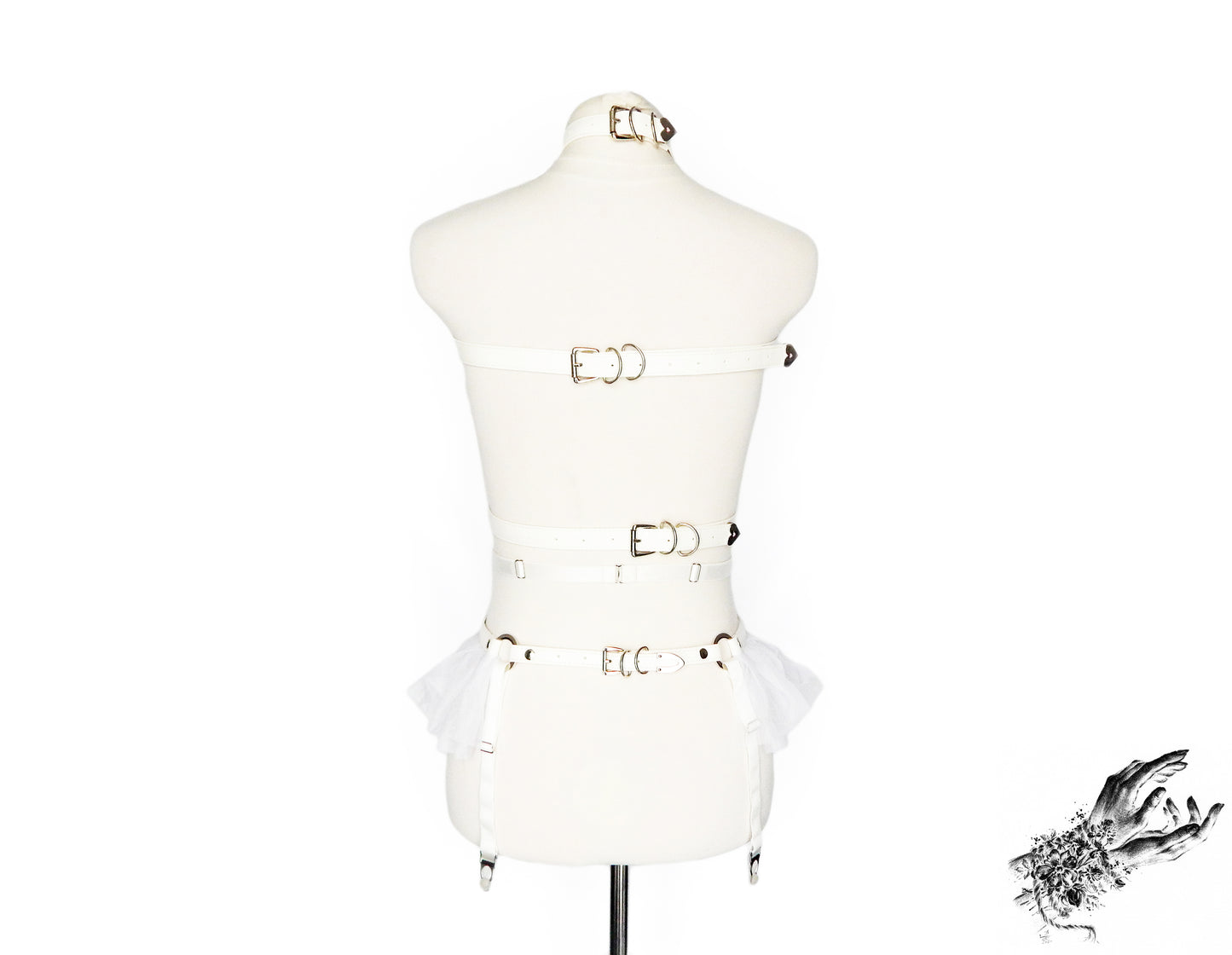 Rear view of a white faux leather harness set featuring a separate chest harness and garter belt showing the adjustable elastic waist and suspender straps and faux leather buckled back straps, displayed on a mannequin against a white background.