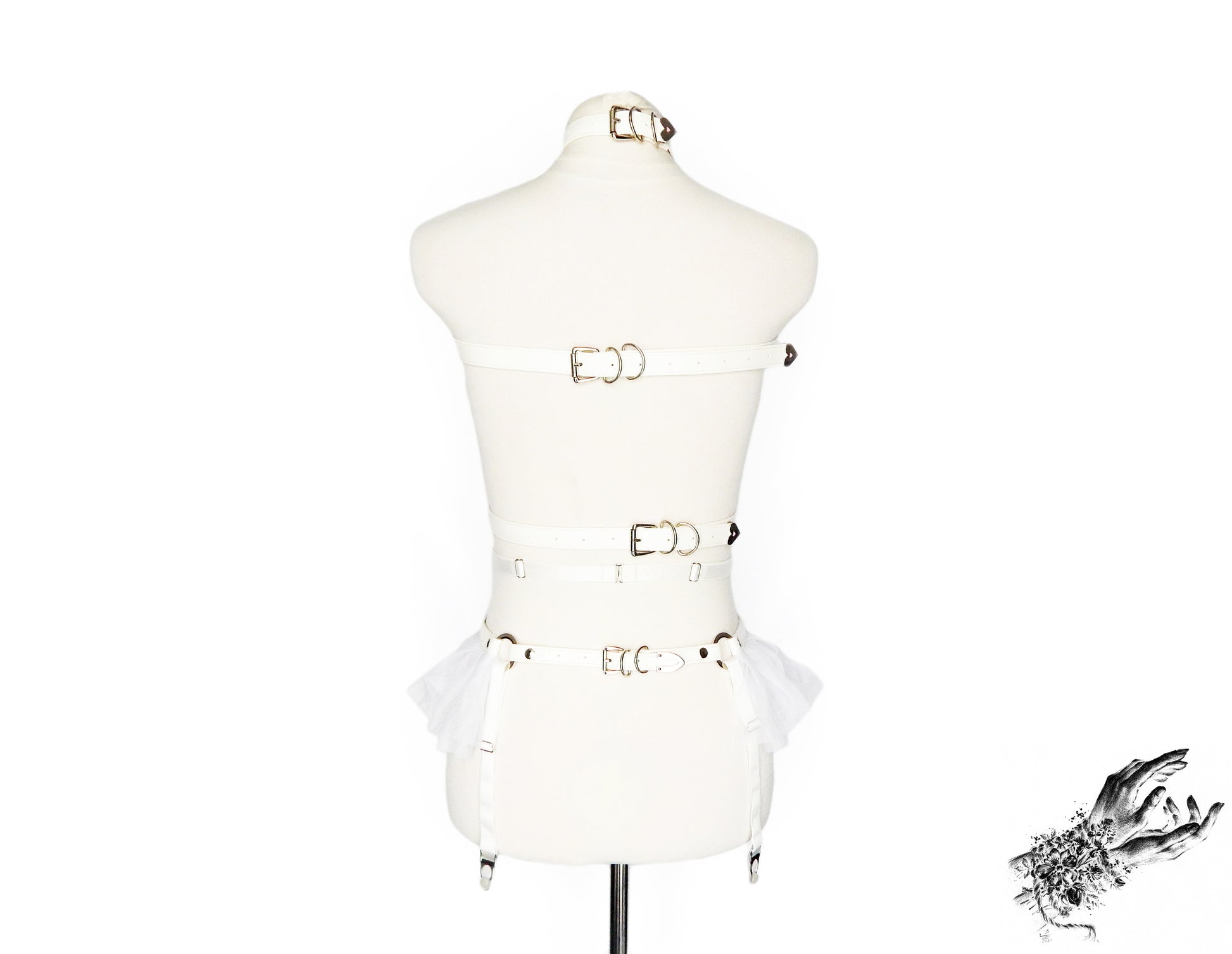 Rear view of a white faux leather harness set featuring a separate chest harness and garter belt showing the adjustable elastic waist and suspender straps and faux leather buckled back straps, displayed on a mannequin against a white background.