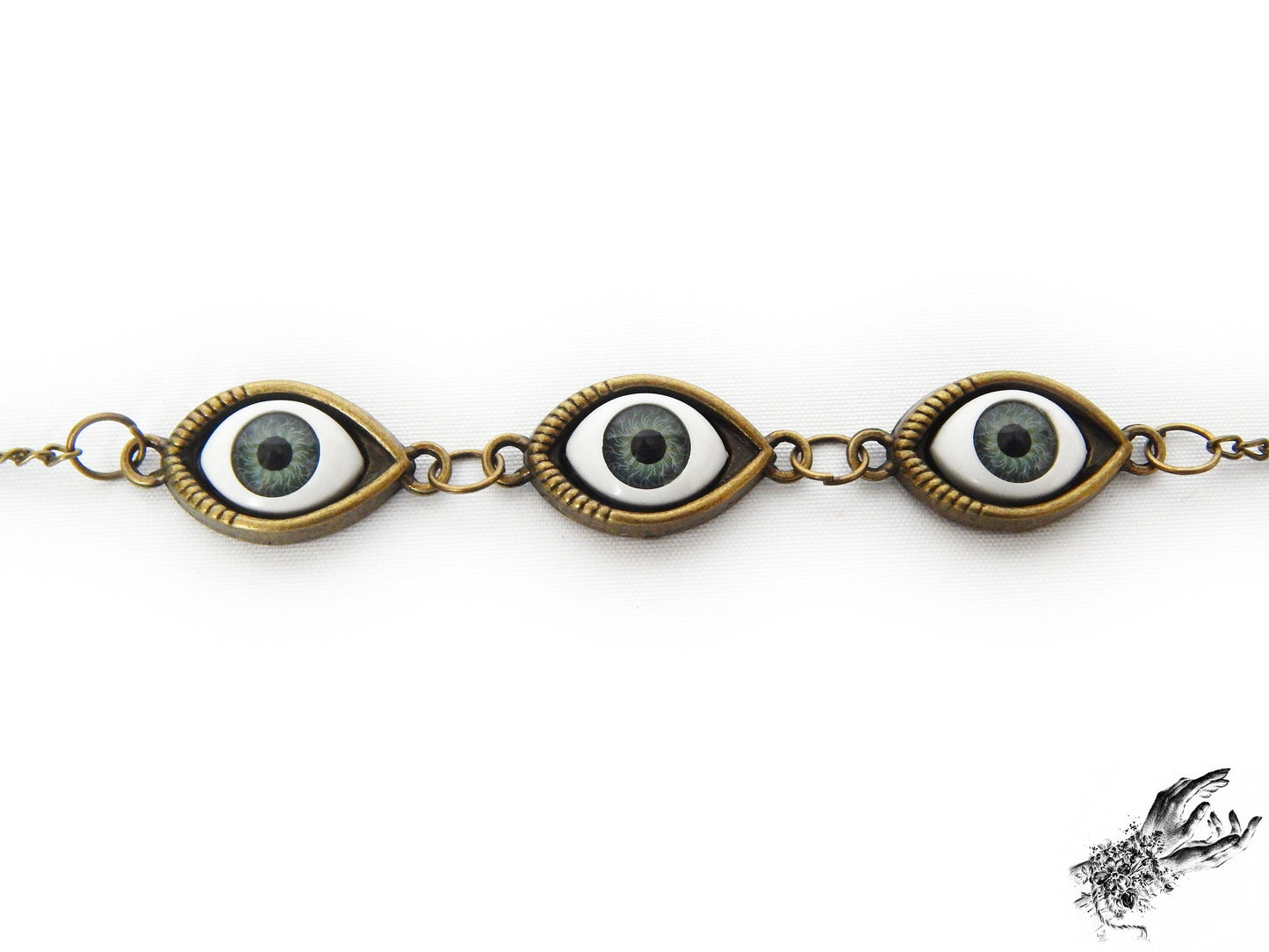 Close-up of the antique bronze evil eye bracelet showing striking green irises in bronze cameo frames for a vintage fashion aesthetic, displayed on a white background