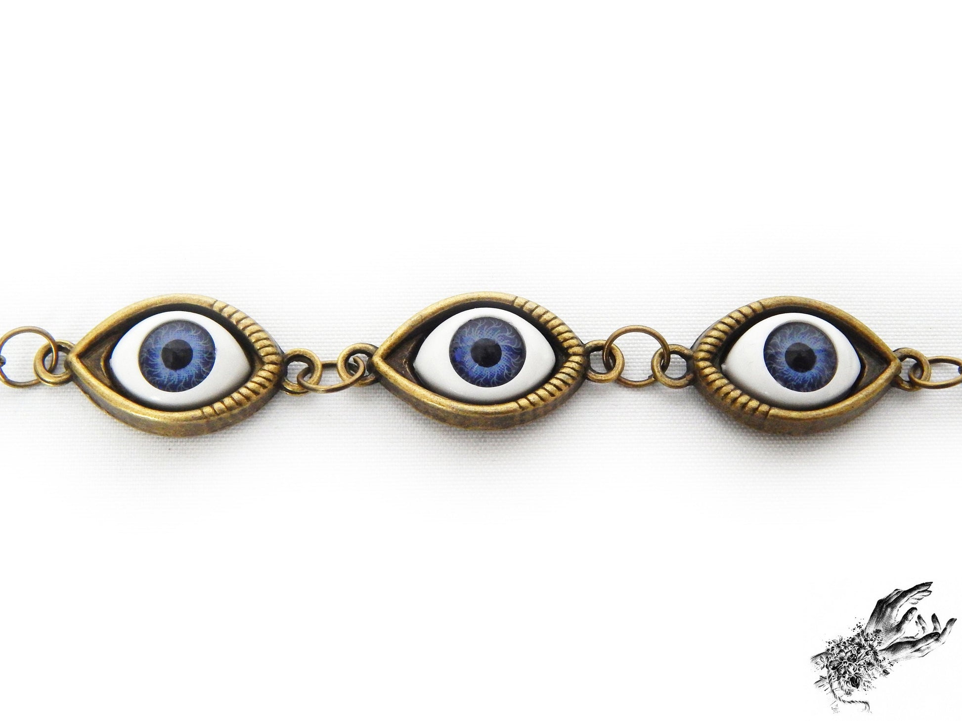 Close-up of the antique bronze evil eye bracelet, showing navy blue irises in bronze cameo frames, creating a vintage fashion aesthetic