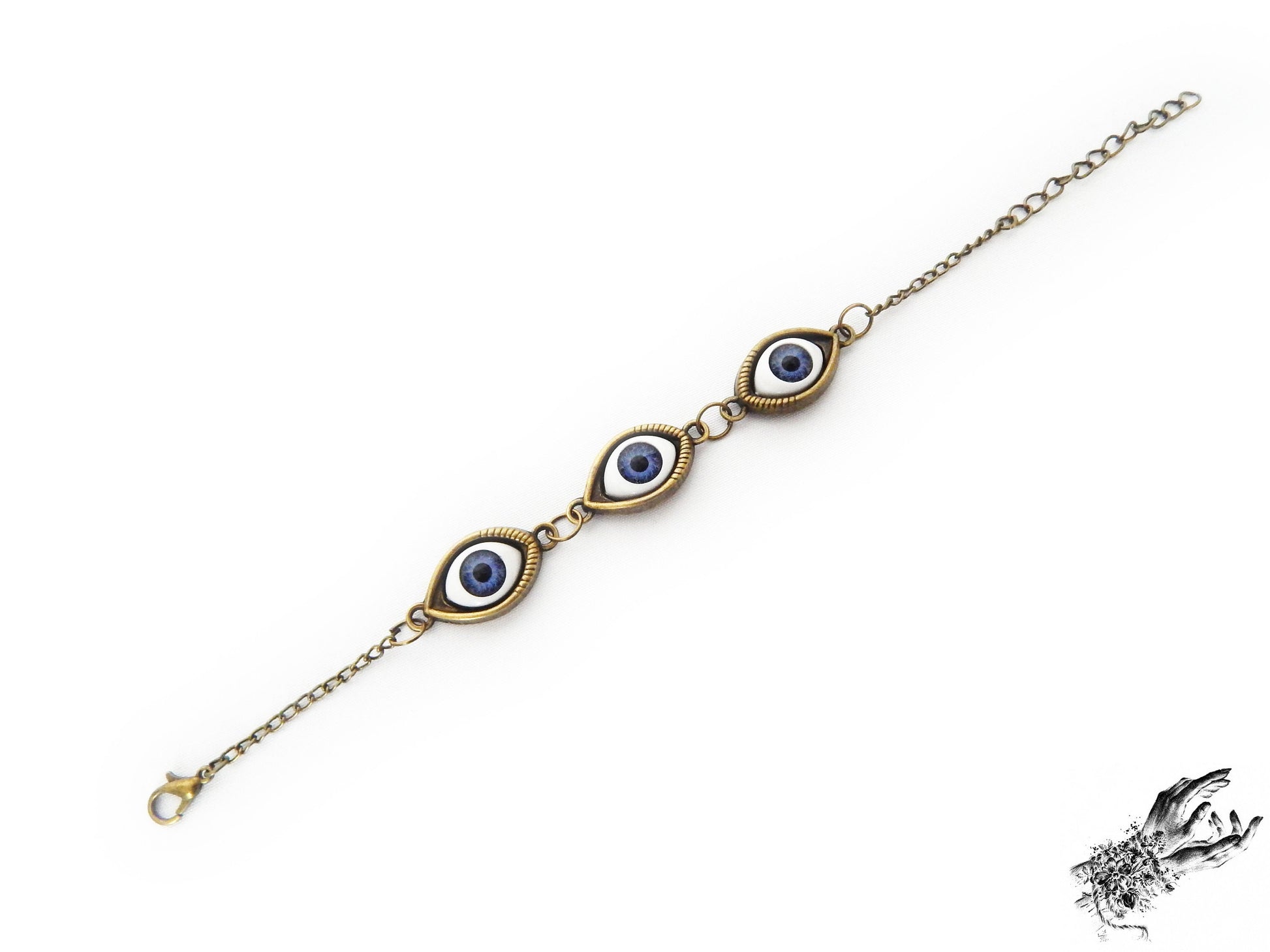 Antique bronze evil eye bracelet with navy blue irises in bronze cameo frames displayed on a white background and inspired by vintage fashion