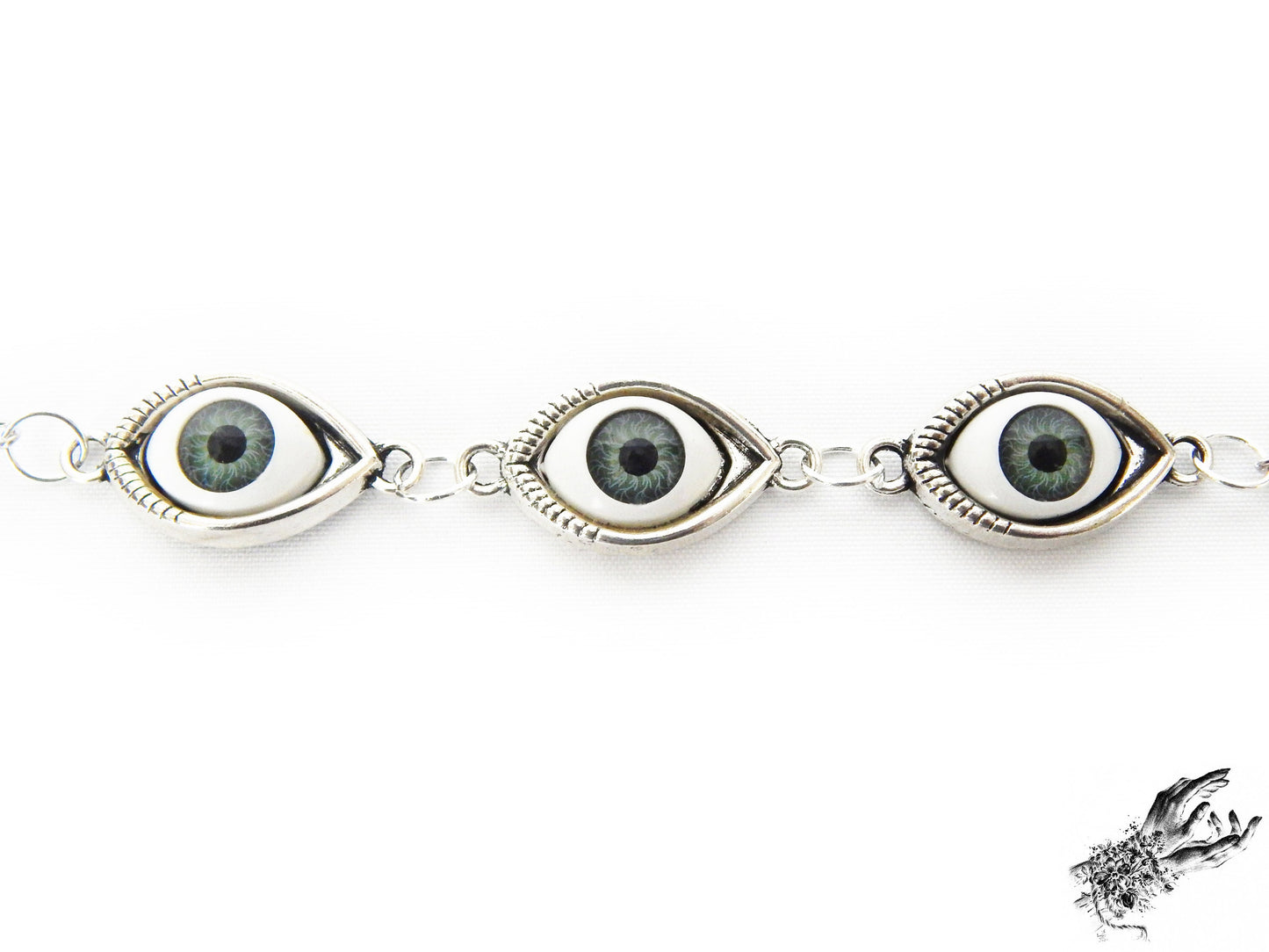 Close-up of the antique silver evil eye bracelet showing striking green irises in silver cameo frames for a vintage fashion aesthetic, displayed on a white background