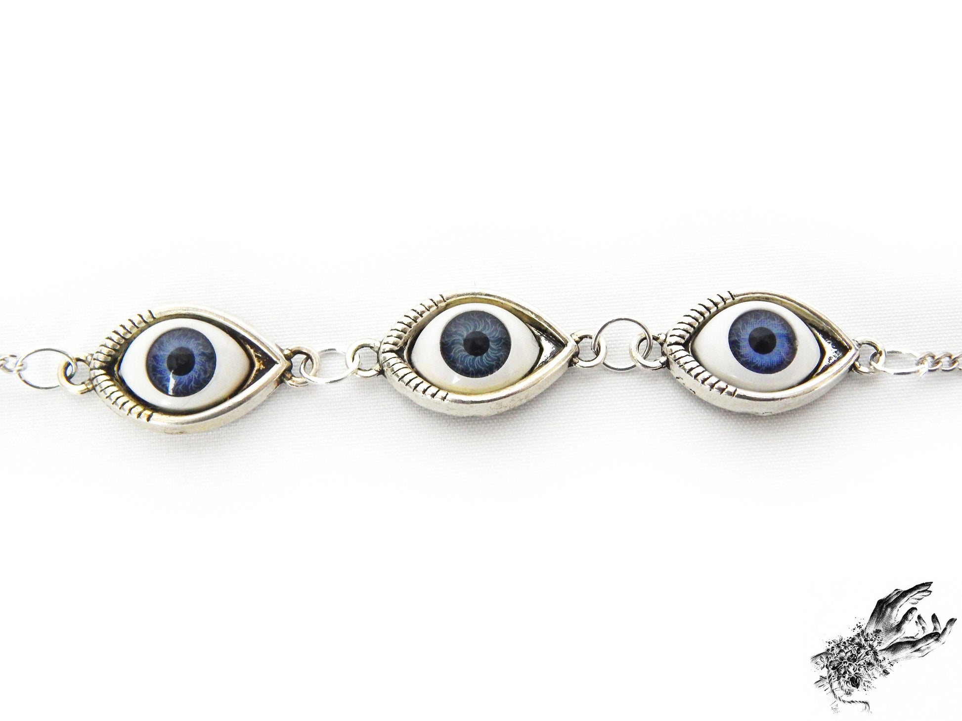 Close-up of the antique silver evil eye bracelet, showing navy blue irises in silver cameo frames, creating a vintage fashion aesthetic