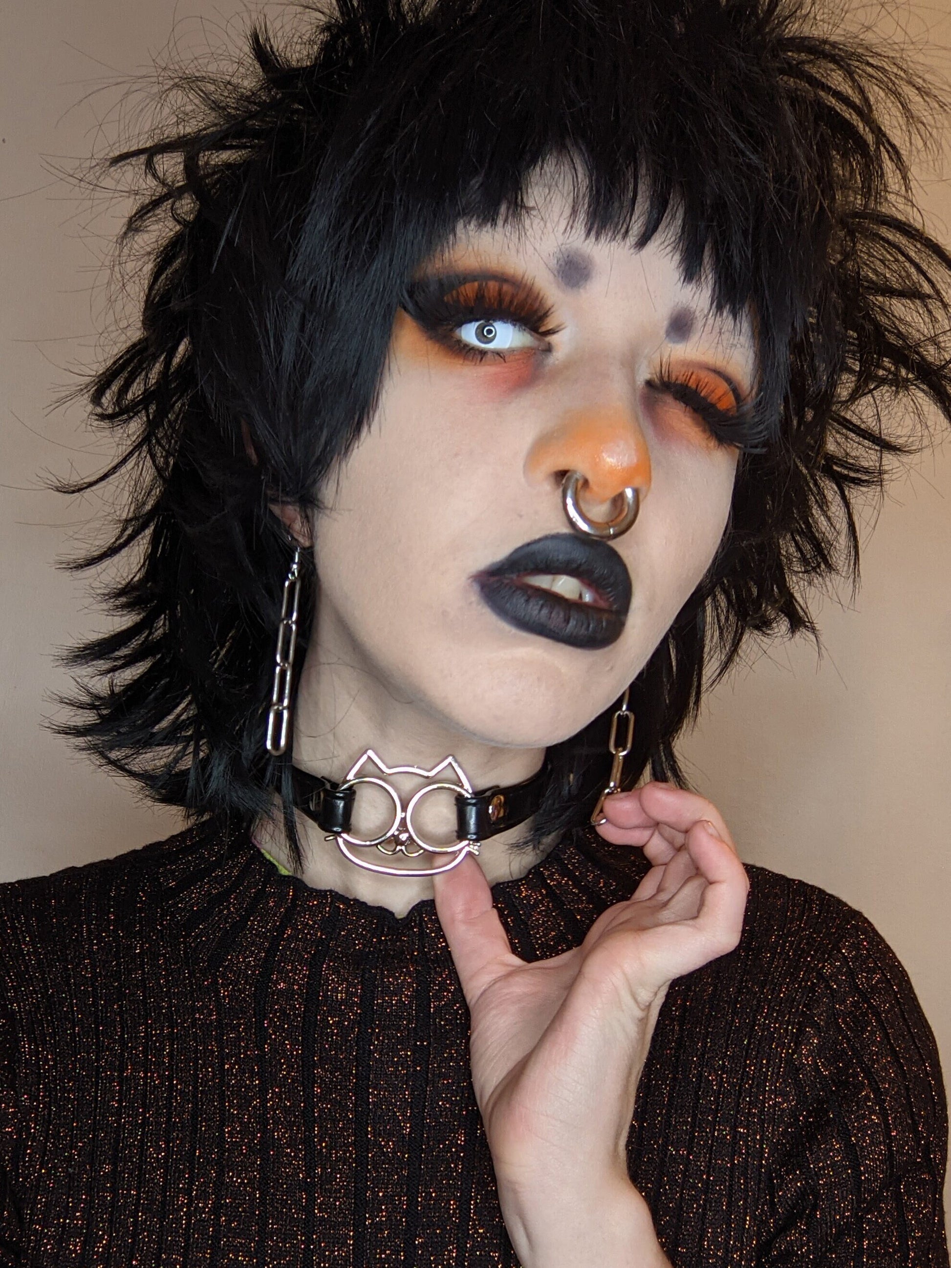 Modelled photo of the black faux leather cat charm choker, styled with bold black and orange gothic make-up and chain earrings for a gothic fashion aesthetic