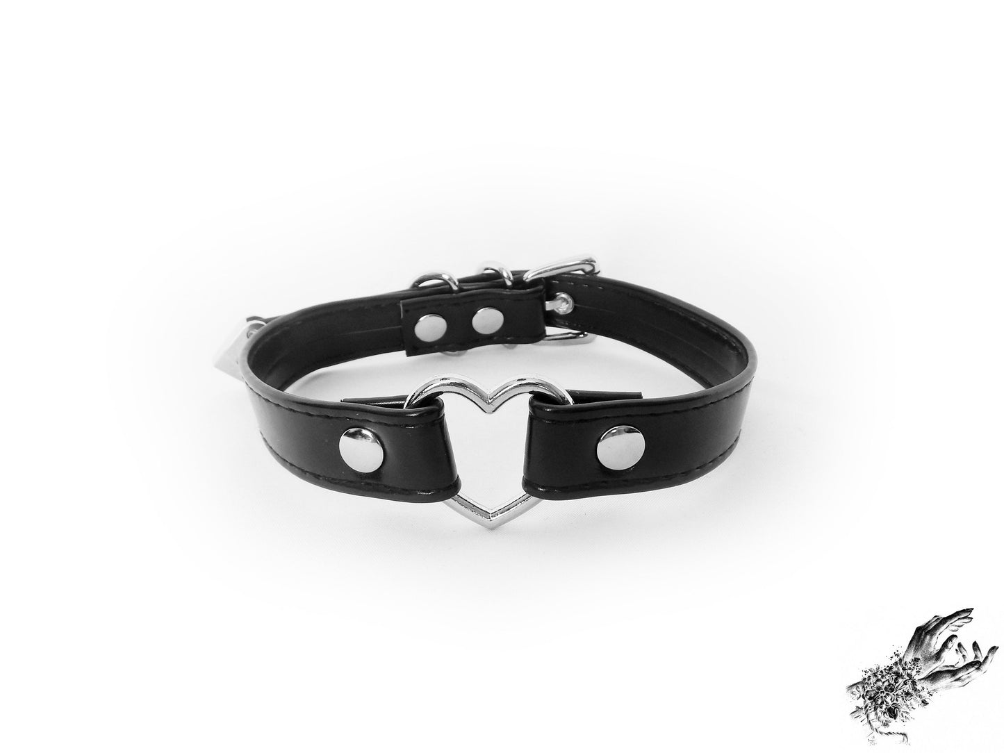Black faux leather choker featuring a central silver tone heart ring, stainless steel plated hardware and adjustable buckle fastening at the back. Displayed on a white background.