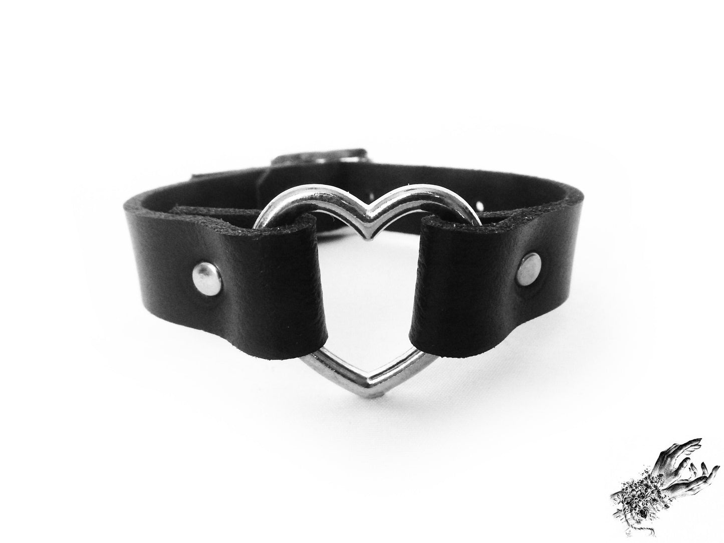Close-up of the black gothic wristband, featuring a central silver heart ring and durable silver rivets on a white background