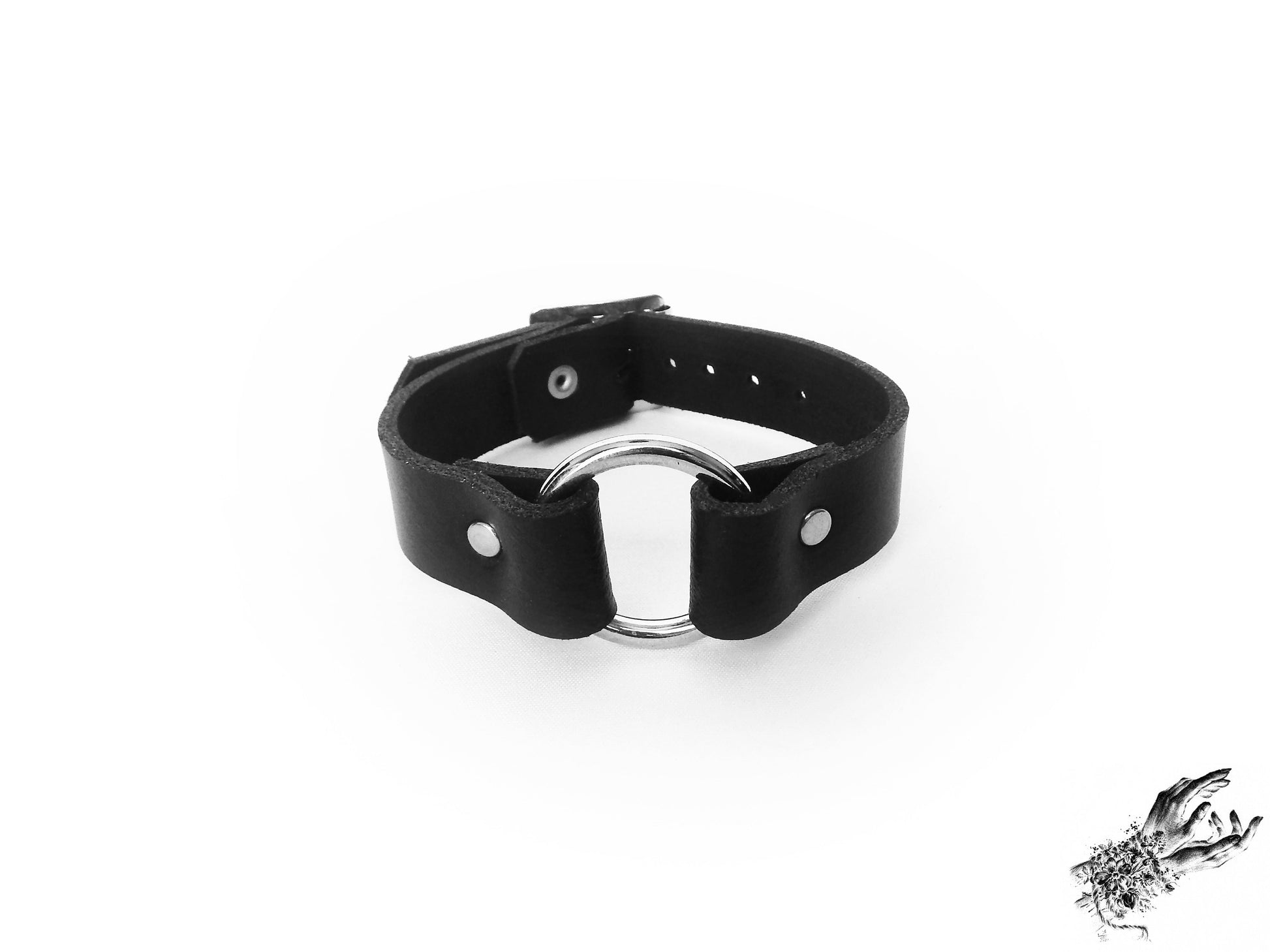 Black leather wristband featuring a central silver O ring and adjustable buckle on a white background