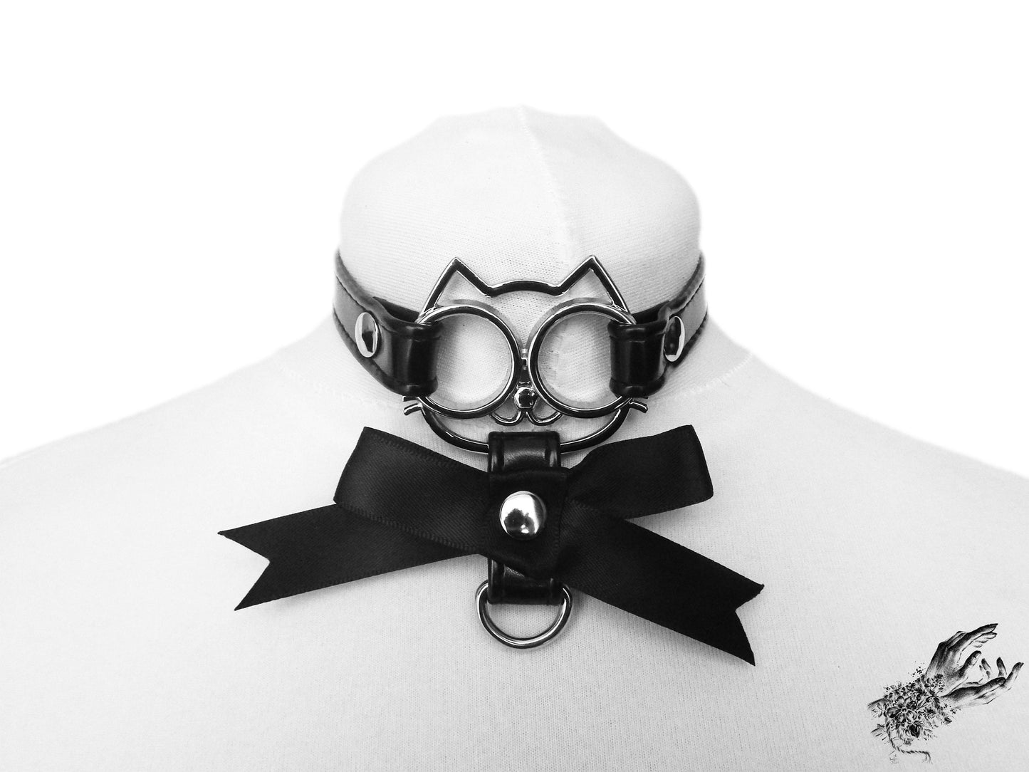 Black faux leather choker featuring a central silver cat shaped pendant and black satin ribbon charm, displayed on a white mannequin bust