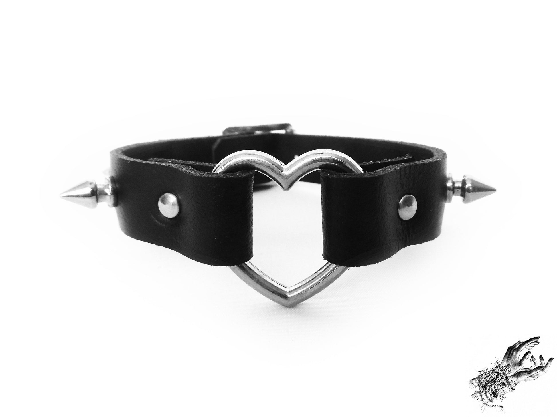 Close-up of the black studded heart ring wristband, showing the central silver heart ring, bold 13mm spike studs and durable silver rivets