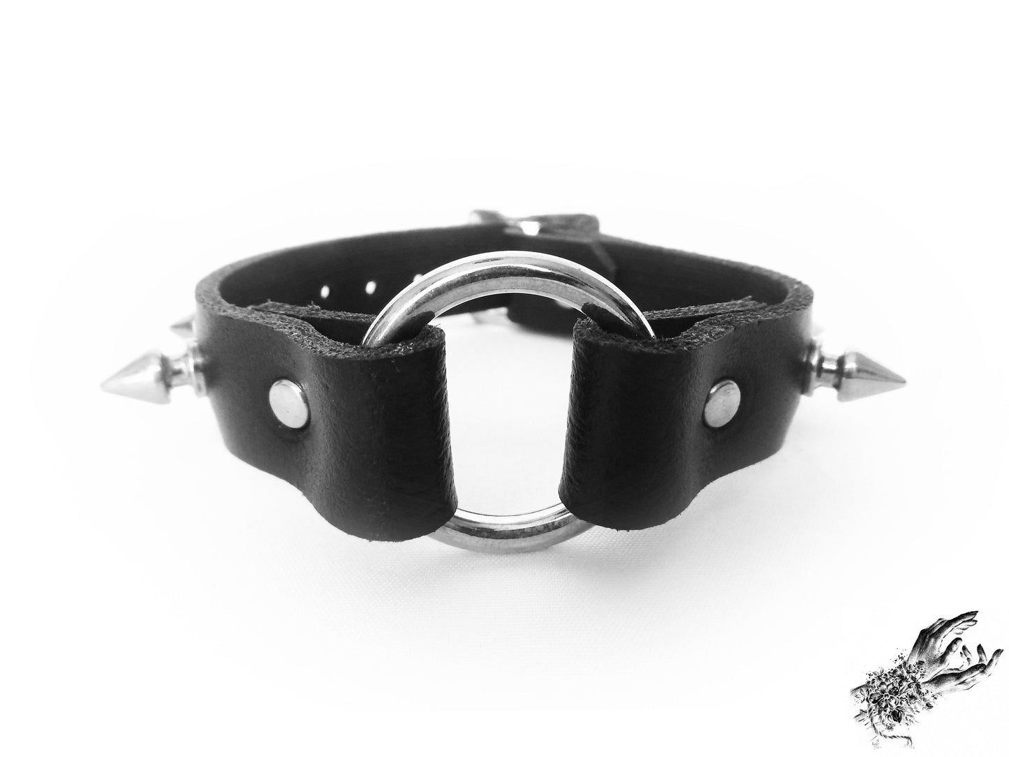 Close-up of the black studded o ring wristband, showing the central silver O ring, bold 13mm spike studs and durable silver rivets on a white background