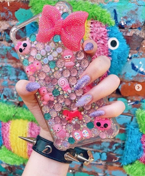 Modelled photo of the black spike studded wristband, styled with pastel goth nails and phone case