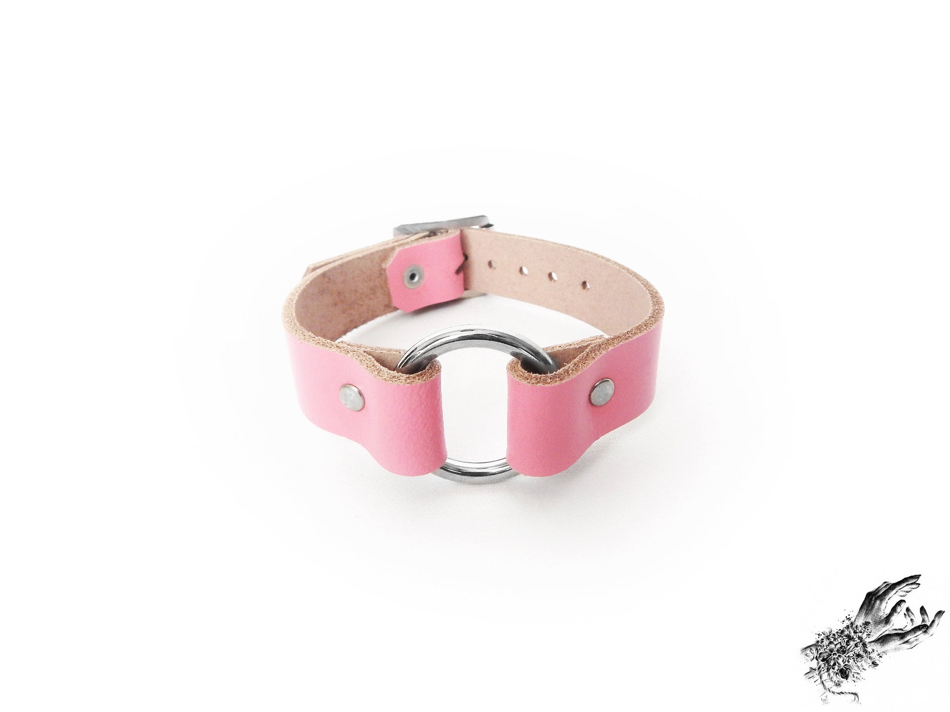 Pink leather wristband featuring a central silver O ring and adjustable buckle on a white background
