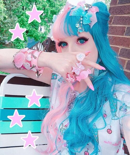 Modelled photo of pink spike stud wristband, styled with pink and blue hair and kawaii plastic accessories for a Fairy Kei fashion