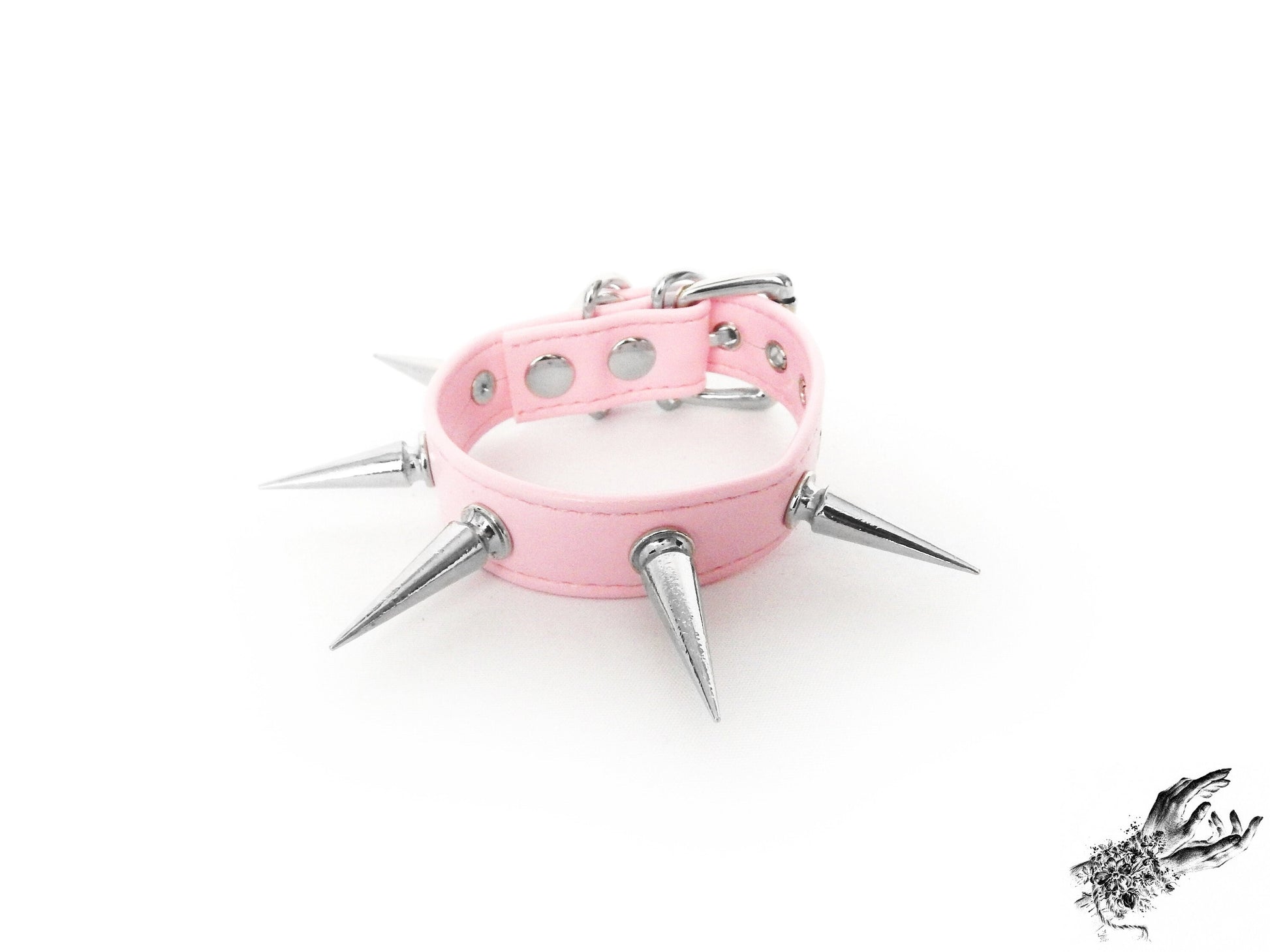 Pink spike studded wristband featuring a faux leather strap and silver 25mm spike studs on a white background