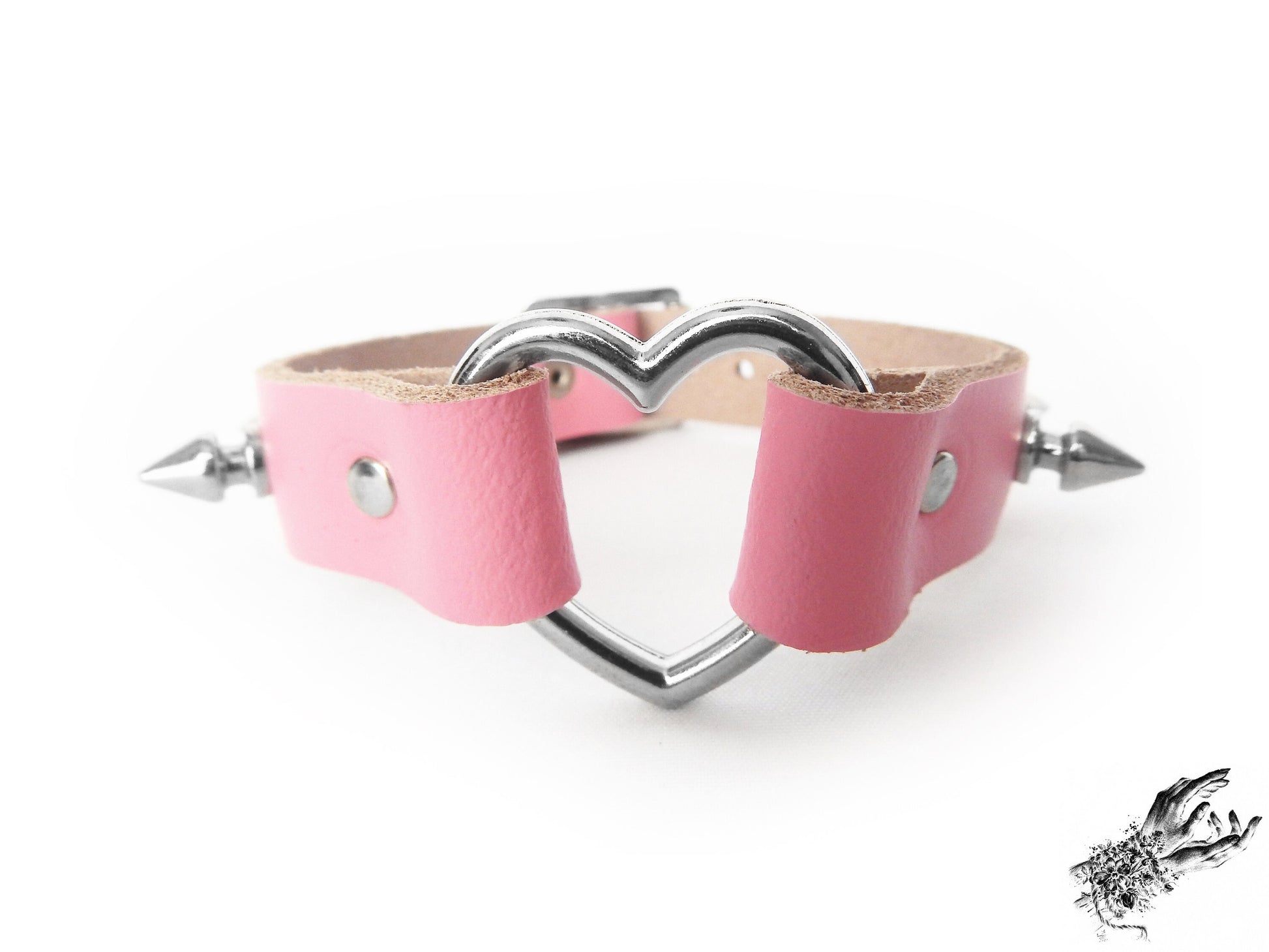 Close-up of the pink studded heart ring wristband, showing the central silver heart ring, bold 13mm studs and durable silver rivets on a white background