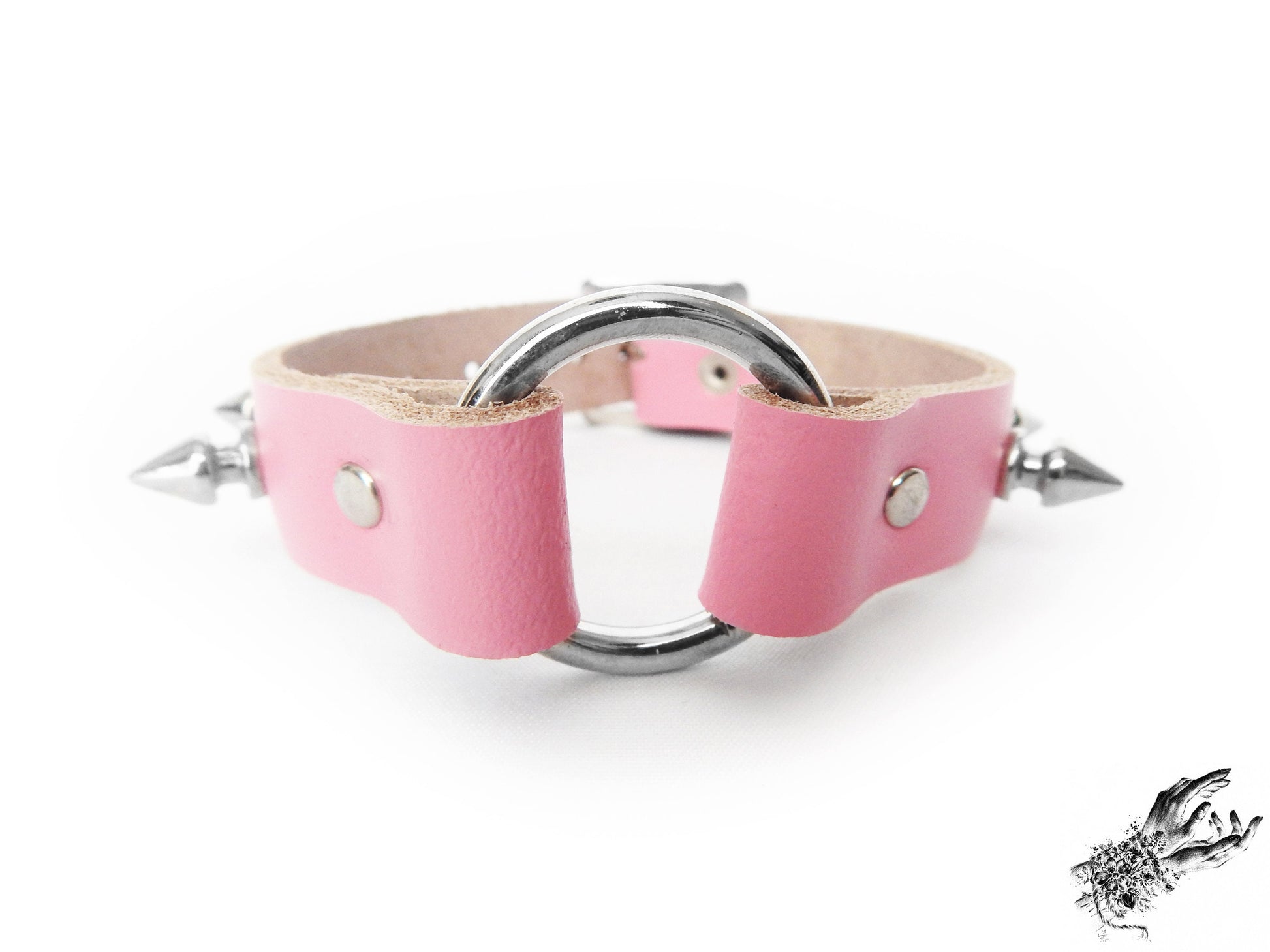 Close-up of the pink studded O ring wristband, showing the central silver O ring, bold 13mm spike studs and durable silver rivets on a white background