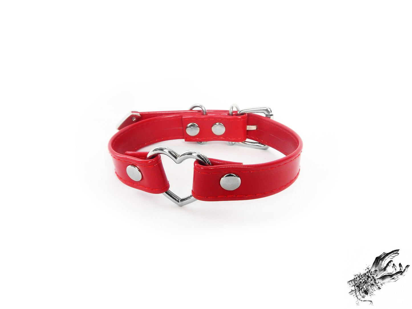 Red faux leather choker featuring a central silver tone heart ring and stainless steel plated hardware, with a buckle fastening and multiple sizing holes at the back. Displayed on a white background.