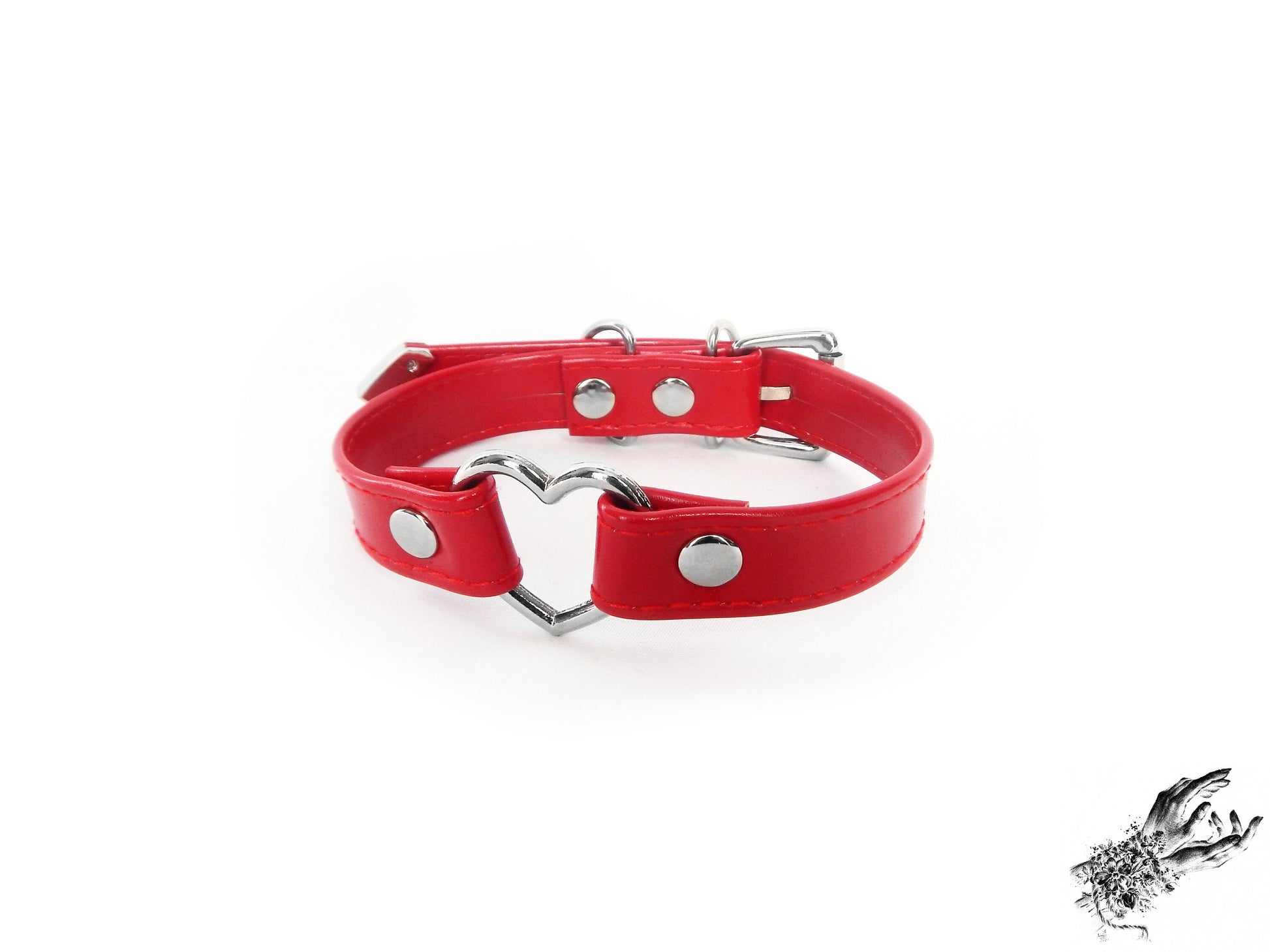 Red faux leather choker featuring a central silver tone heart ring and stainless steel plated hardware, with a buckle fastening and multiple sizing holes at the back. Displayed on a white background.