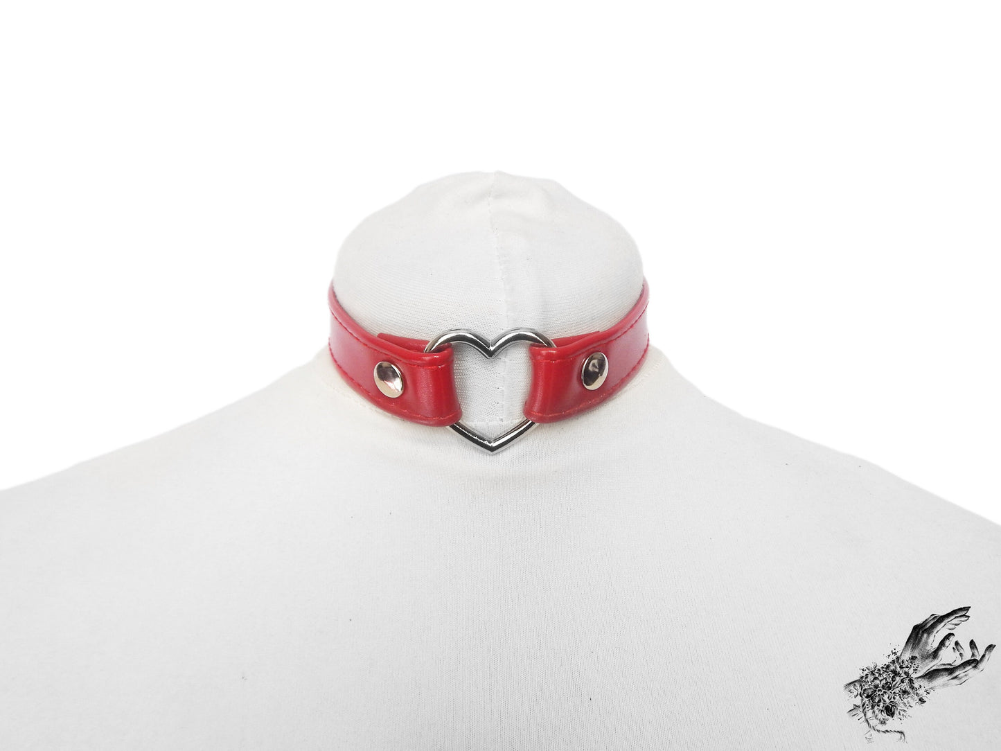 Red faux leather choker featuring a central silver tone heart ring and stainless steel plated hardware, with a buckle fastening and multiple sizing holes at the back. Displayed on a white mannequin bust against a white background.
