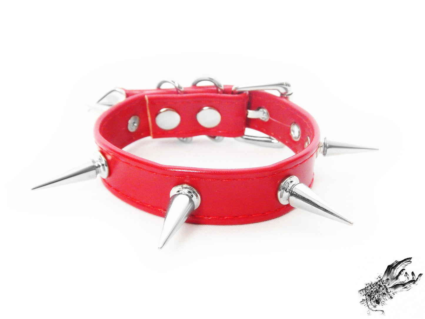Close-up of red spike studded wristband, showing the supple faux leather strap and silver 25mm spike studs