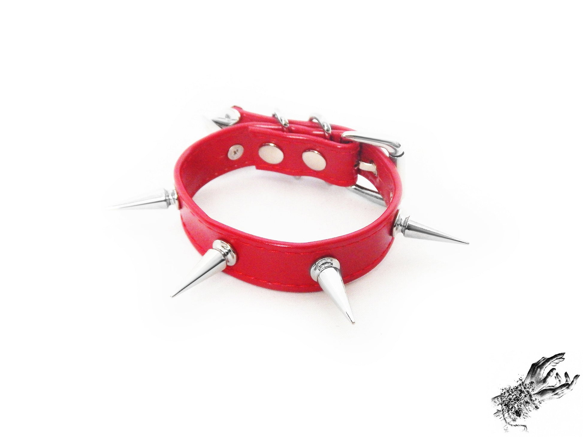 Red spike studded wristband featuring a faux leather strap and silver 25mm spike studs on a white background