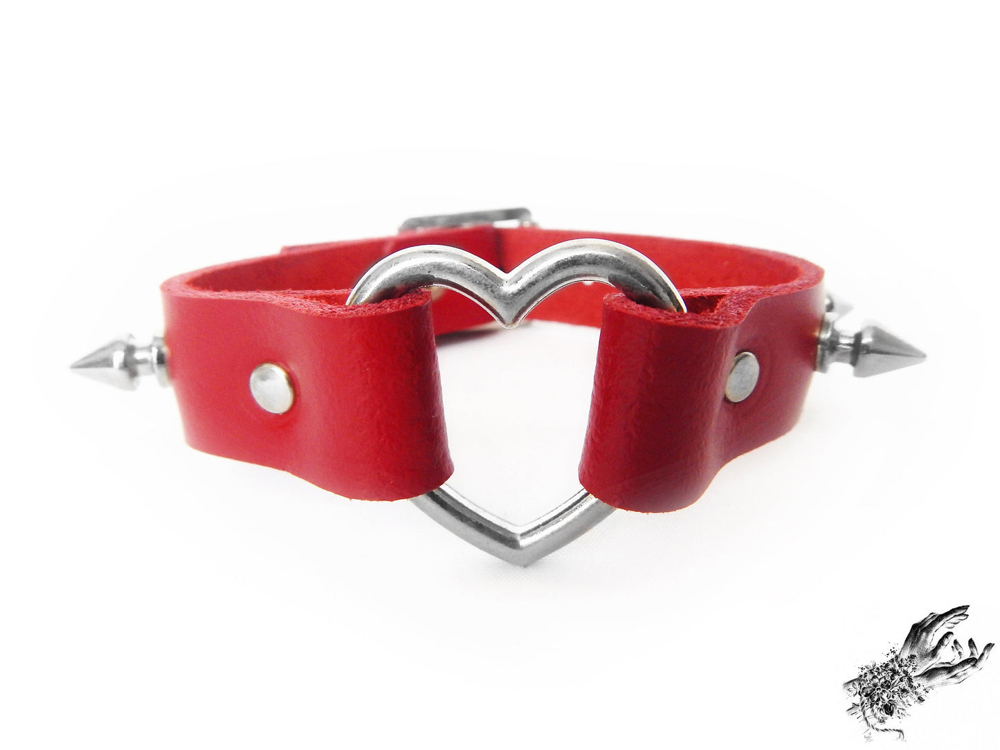 Close-up of the red studded heart ring wristband, showing the central silver heart ring, bold 13mm spike studs and durable silver rivets