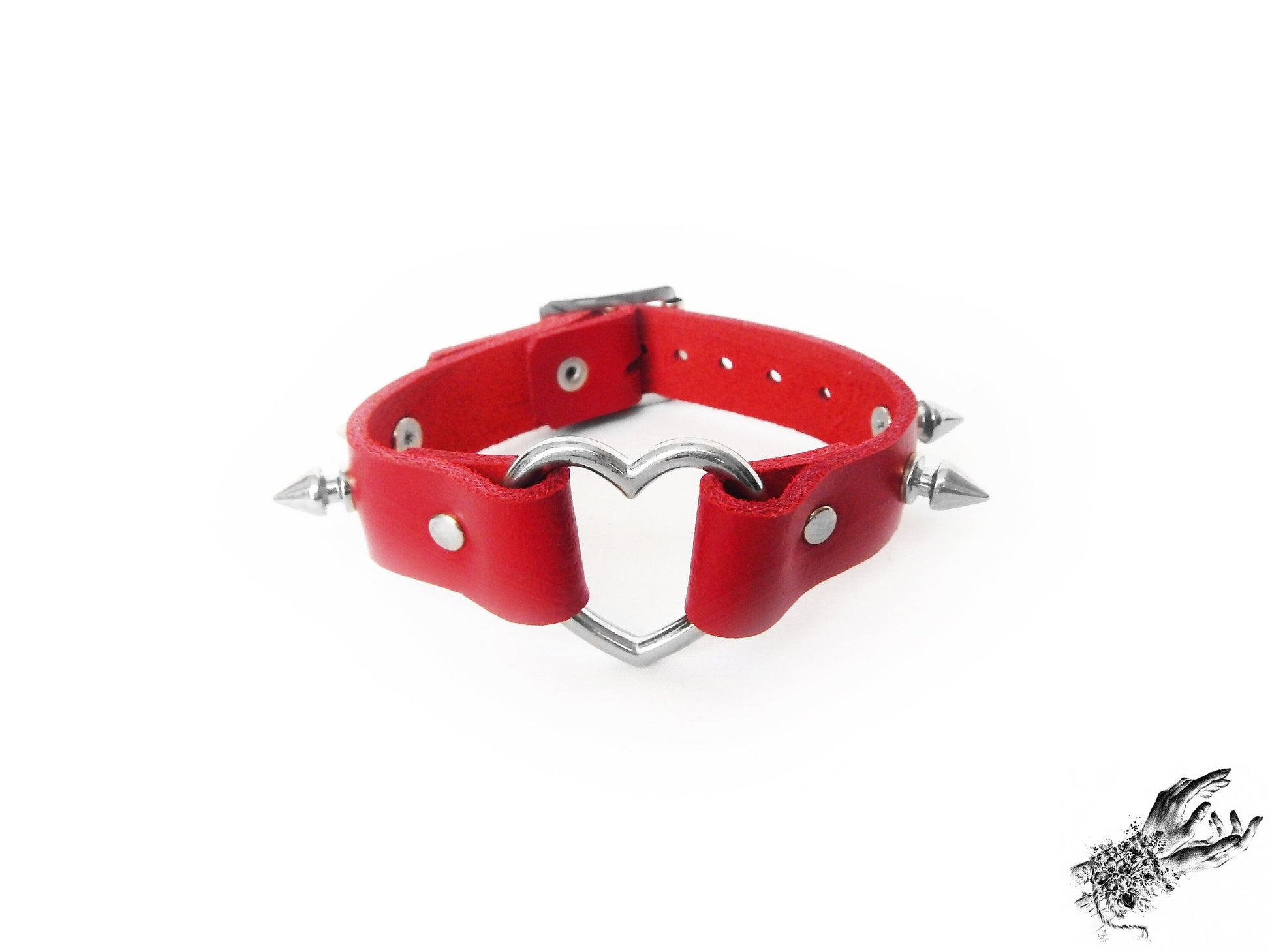 Red studded heart ring wristband featuring a central silver heart ring and bold 13mm spike studs on a white background
