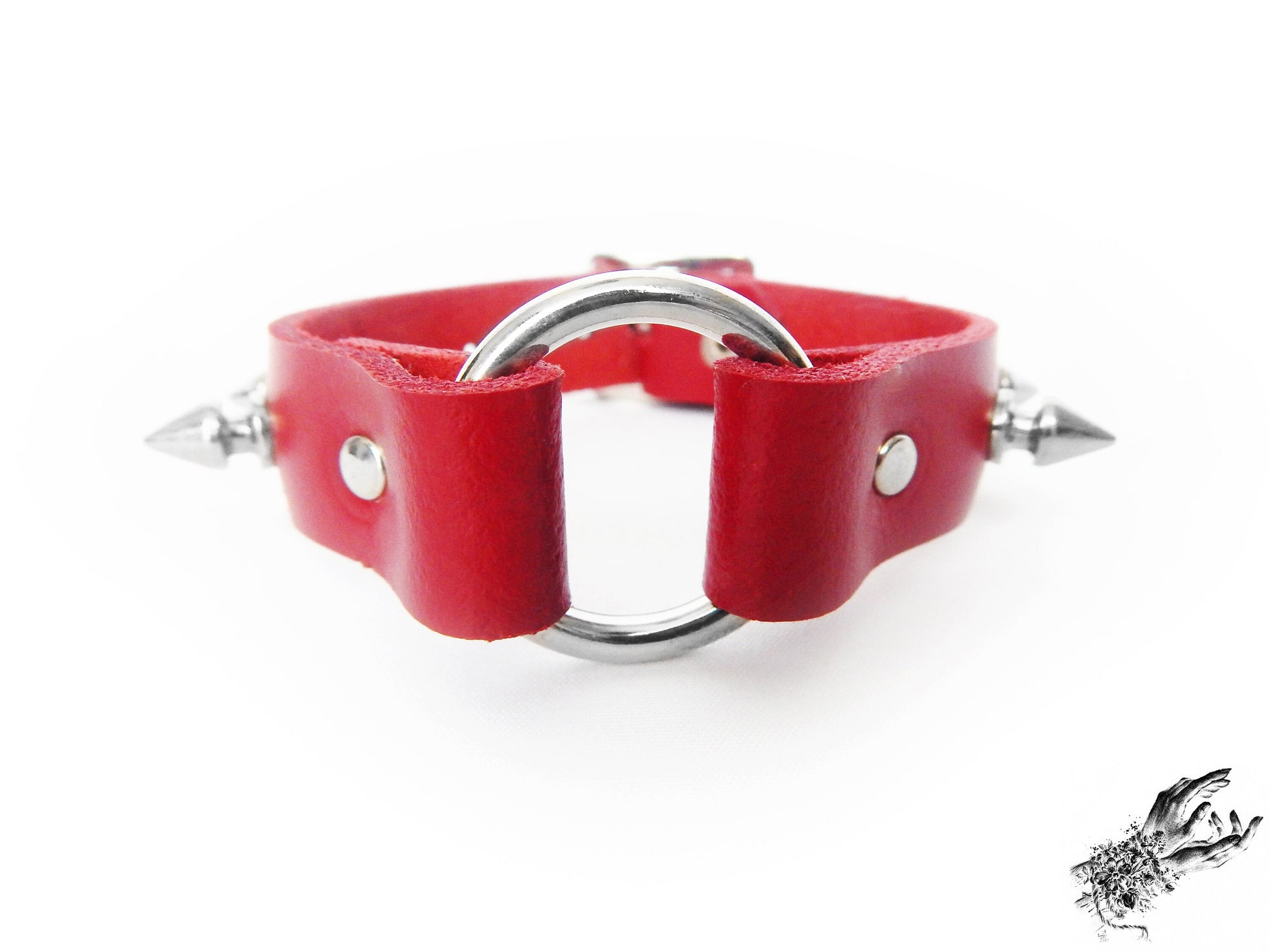 Close-up of the red studded o ring wristband, showing the central silver O ring, bold 13mm spike studs and durable silver rivets