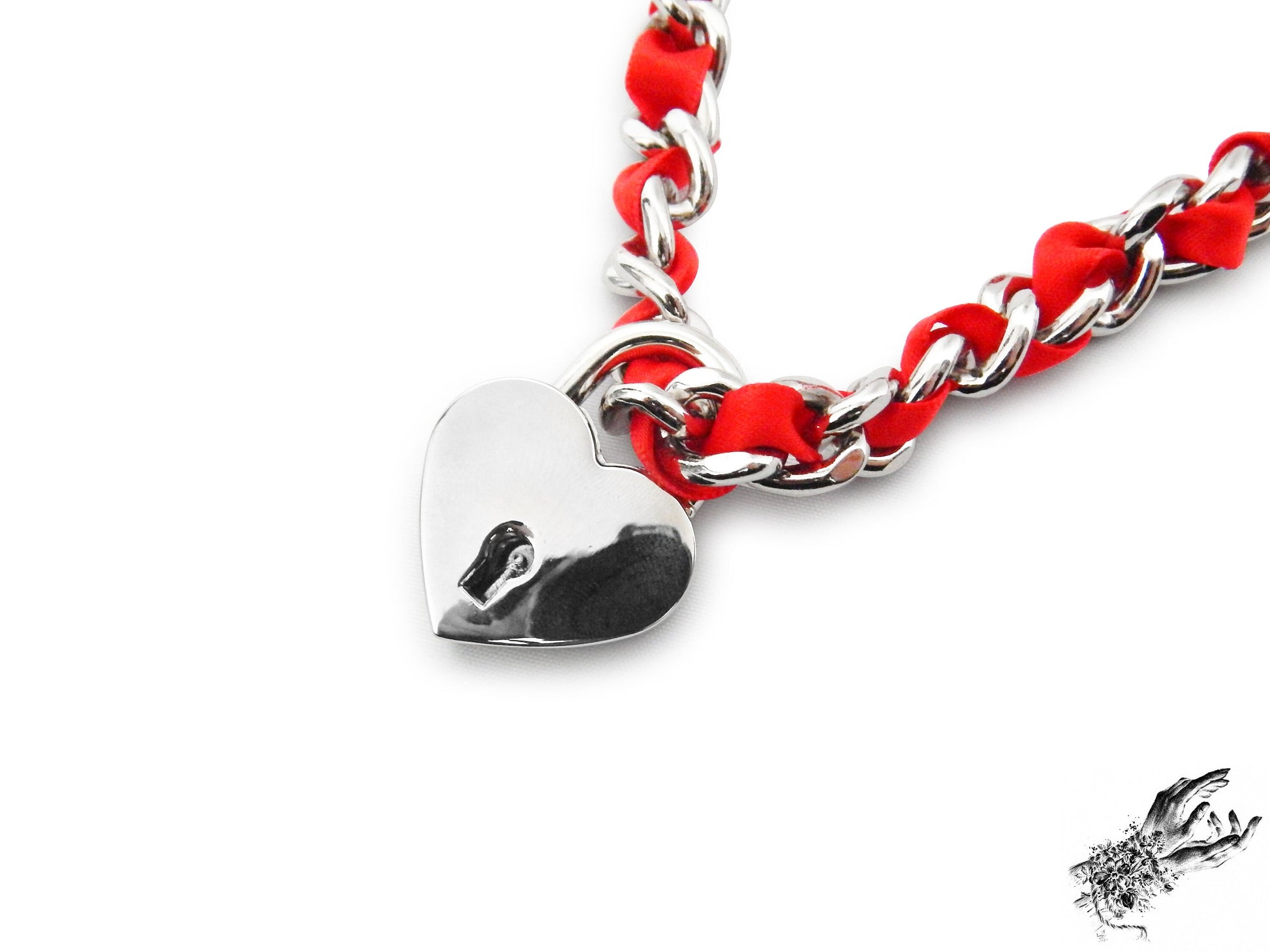 Close-up of a silver chain choker threaded with red satin ribbon, featuring a removable central silver heart padlock with matching key, displayed on a white background.