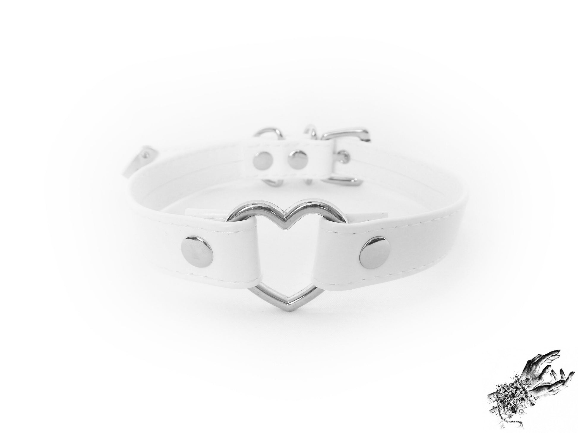 Head-on photo of a white faux leather choker featuring a central silver heart ring and stainless steel plated hardware, with adjustable buckle and sizing holes at the back. Displayed on a white background.