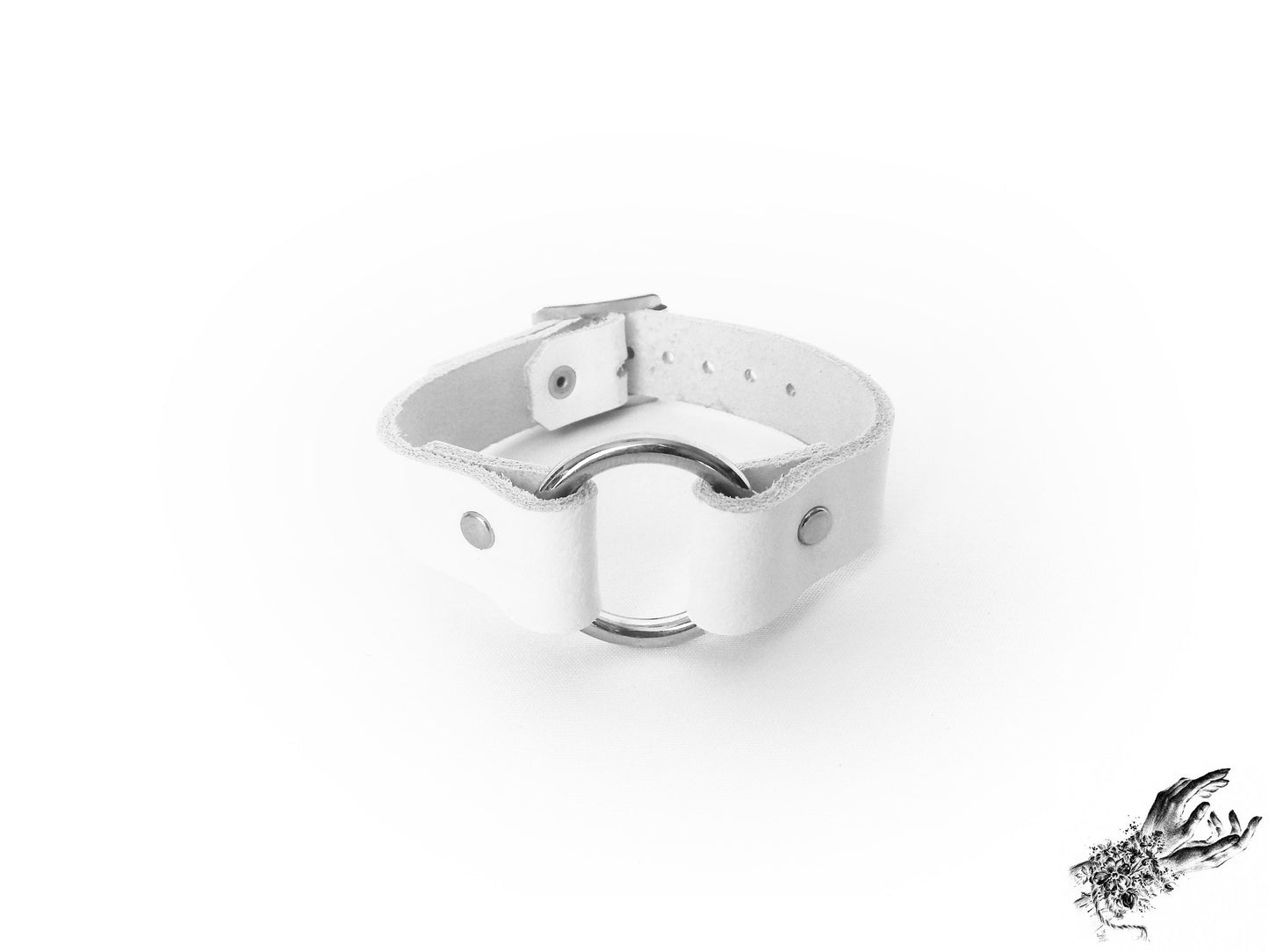 White leather wrisband featuring a central silver O ring and adjustable buckle on a white background