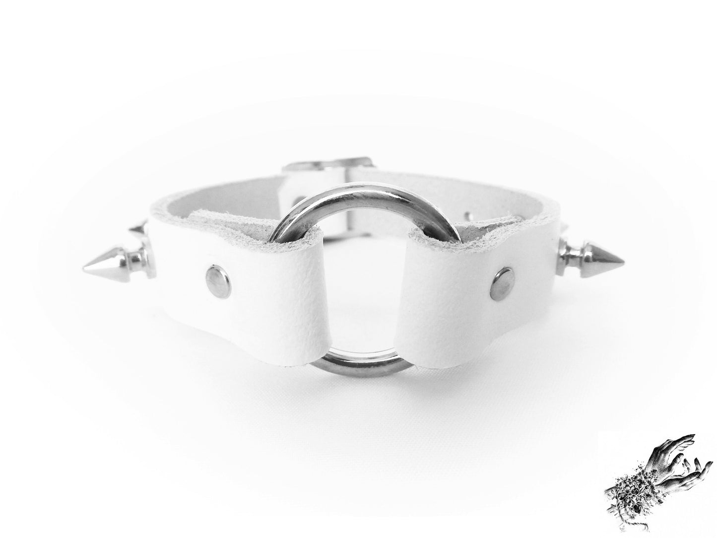 Close-up of the white studded o ring wristband, showing the central silver O ring, bold 13mm spike studs and durable silver rivets for gothic and alt fashion in the UK