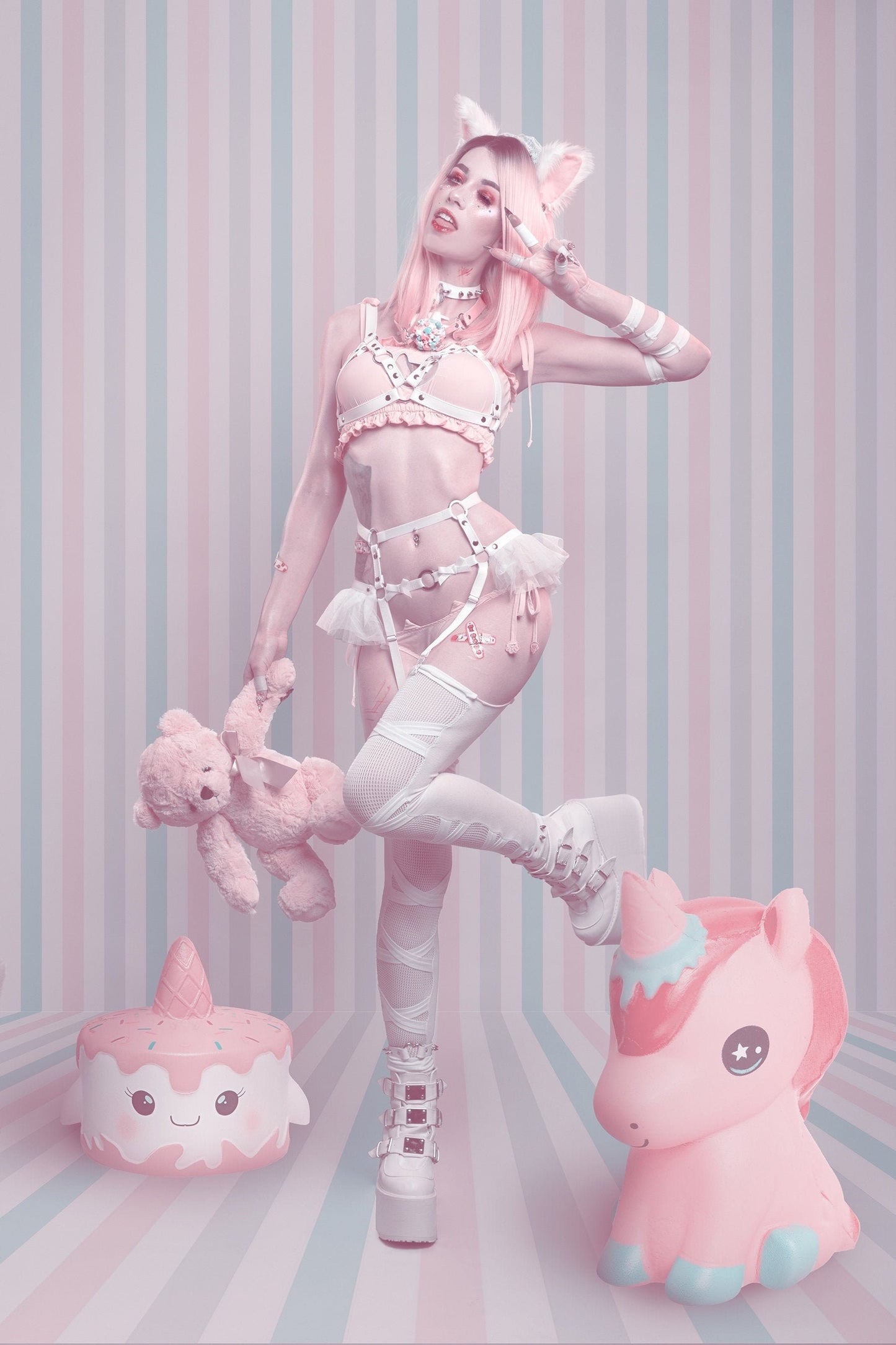 Modelled photo of a white vegan leather harness set featuring silver O ring hardware, ruffled tulle accents and bow appliques at the waist, styled with a white studded choker and pink kawaii lingerie for a pastel goth look.